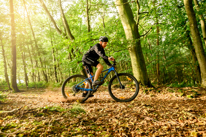 Elev kører mountainbike i skoven ved Kongeådalens Efterskole